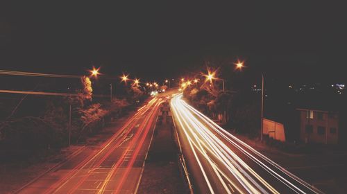 Light trails on road against sky at night