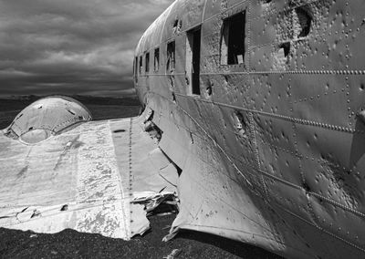 Close-up of airplane on beach against sky during winter