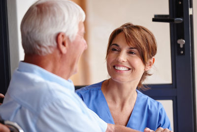 Happy nurse talking to senior patient