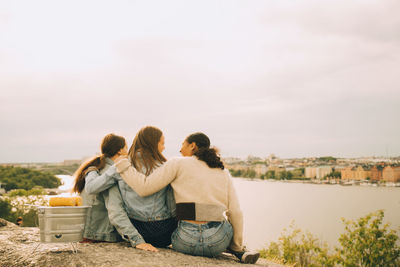 Rear view of people looking at river against sky