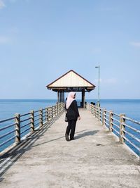 Man standing on pier over sea against sky