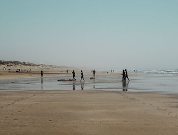 People at beach against clear sky