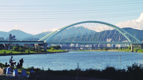 People on bridge against sky