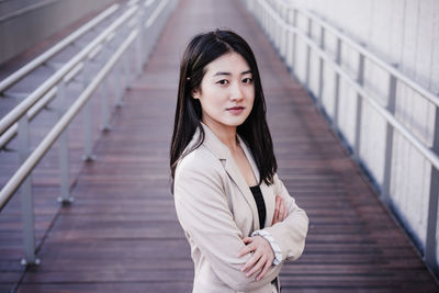 Confident beautiful chinese business woman with arms crossed standing on runway. entrepreneur
