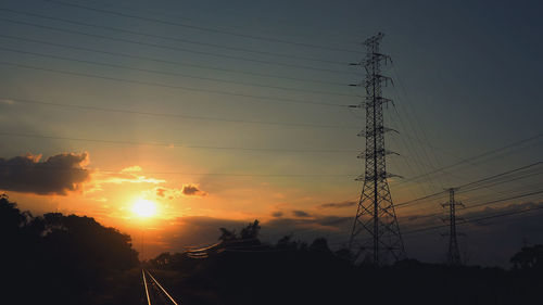 Low angle view of silhouette electricity pylon against sky during sunset