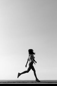 Side view of woman running against clear sky