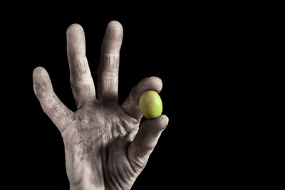 Close-up of hand holding ball against black background