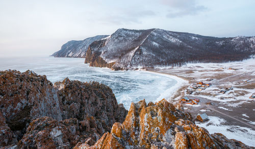 Scenic view of frozen sea by mountain against sky