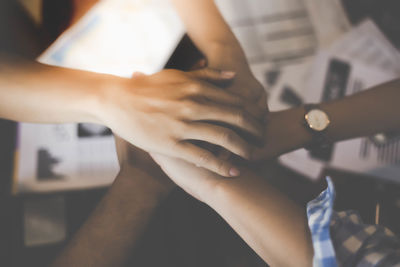 Cropped hands of colleagues stacking hands above office desk