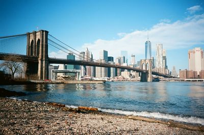 Suspension bridge over river against skyline