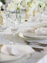 Table serves for banquet. transparent wine glasses, plates and shiny cutlery on white table cloth.