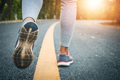 Low section of woman standing on road