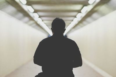 Rear view of man standing in illuminated tunnel