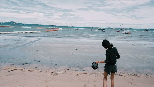 Rear view of man standing on beach against sky