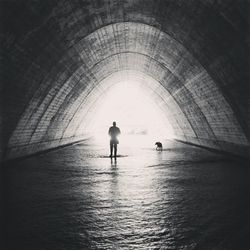 Person with dog standing in sewage tunnel