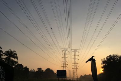 Low angle view of silhouette electricity pylon against sky during sunset