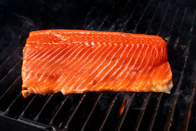 Close-up of fish on barbecue grill against black background