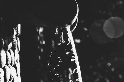 Cropped image of hand holding hanging over black background