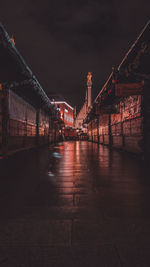 Illuminated bridge over street amidst buildings in city at night