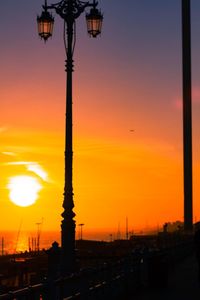 Silhouette of street lights against orange sky
