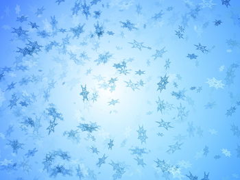 Low angle view of snowflake against blue sky