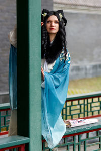 Portrait of smiling young woman standing by railing