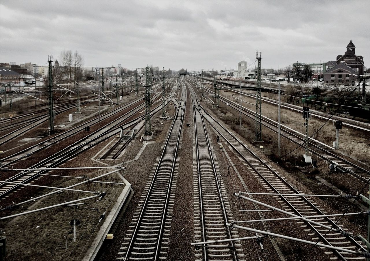 railroad track, rail transportation, transportation, built structure, architecture, sky, public transportation, diminishing perspective, the way forward, building exterior, vanishing point, cloud - sky, high angle view, railway track, railroad station, city, connection, railroad station platform, metal, day