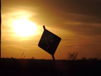 Silhouette road sign against sky during sunset