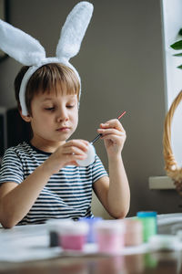 Cute little boy colouring eggs for easter