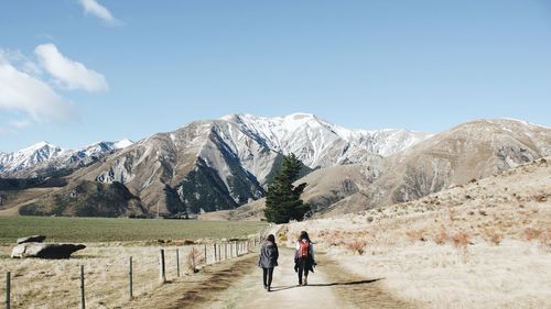 Rear view of people walking on mountain against sky