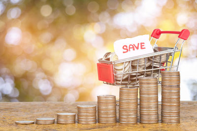 Close-up of coins with miniature shopping cart on table