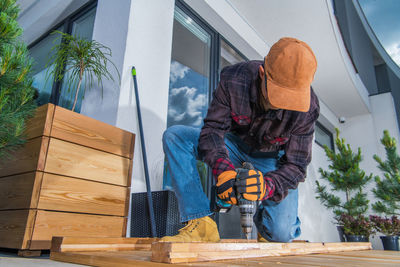 Low angle view of carpenter working by building outdoors