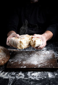 Close-up of person breaking bread at counter