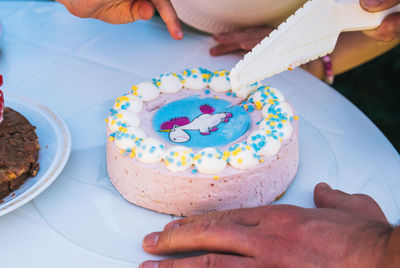 Close-up of man cutting birthday cake on table