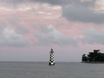 Lighthouse by sea against sky