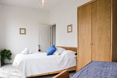 Bed base, bedroom with mat on the floor, clay pot in the background, wooden credenza and mirror. 