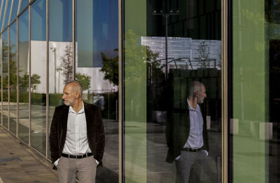 Portrait of adult man in suit against glass wall