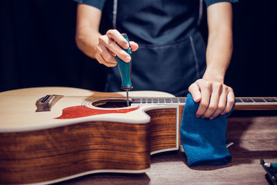 Midsection of man playing guitar on table