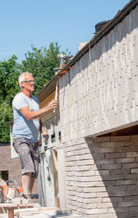 Masonry worker the bricklayer makes the facade of the house from gray bricks