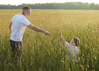 Rear view of woman with arms outstretched on field