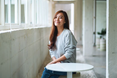 Portrait of young woman standing against wall