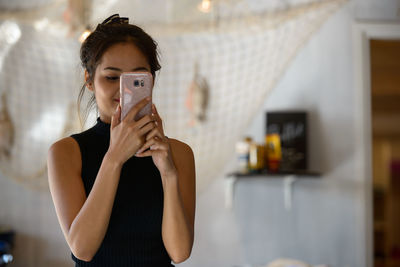 Young woman using mobile phone at home