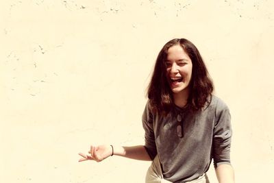 Beautiful smiling young woman standing against wall