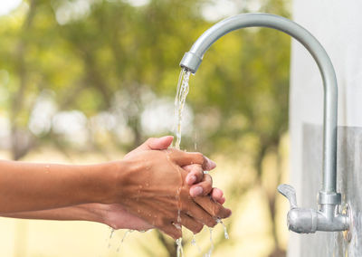 Cropped image of woman washing hands with faucet water