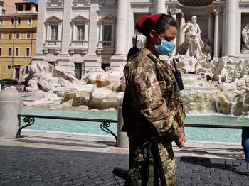 Woman standing by statue against building in city