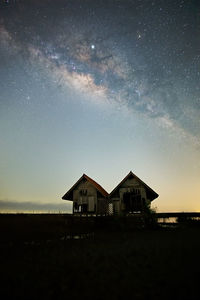 Houses by building against sky at night