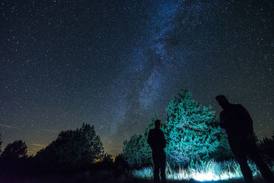 Silhouette man standing by tree against sky at night