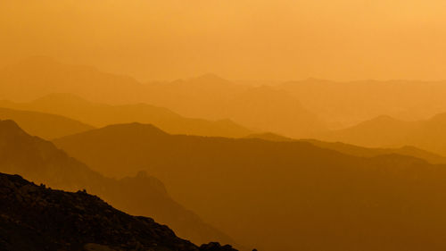 Scenic view of silhouette mountains against orange sky