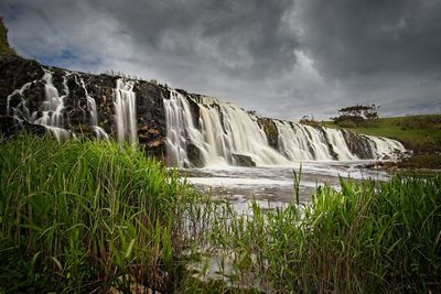 Scenic view of waterfall against sky