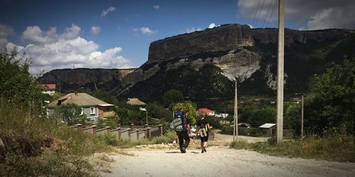 Rear view of hikers walking on road against sky